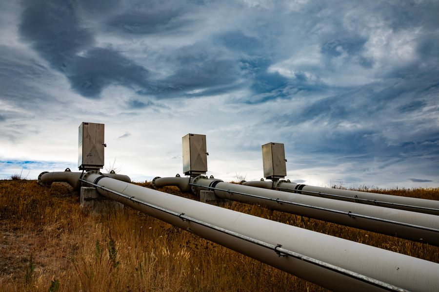 Pipelines running across open land under a stormy sky